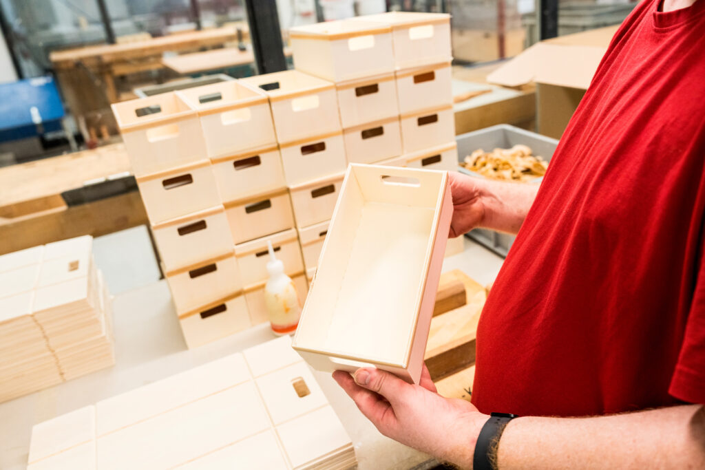 Mitarbeiter hält die Holzkiste für den Mutz in der Hand